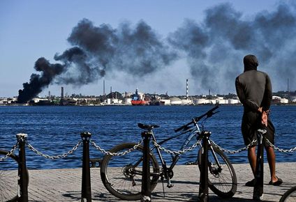 Un hombre observa la columna de humo que emana de la refinería Ñico López en La Habana.
