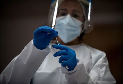 Una trabajadora de la salud sostiene una muestra de hisopo durante una prueba masiva de COVID-19
