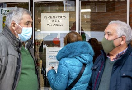 Personas utilizan mascarillas frente a un centro de salud.